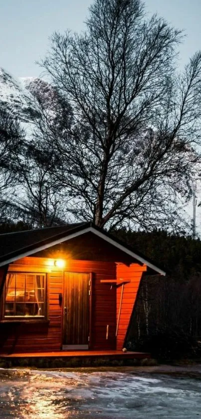 Cozy cabin at night with snowy mountain backdrop.