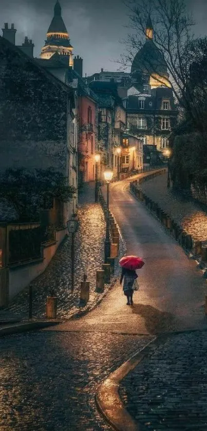 Quaint cobblestone street with a red umbrella at night.