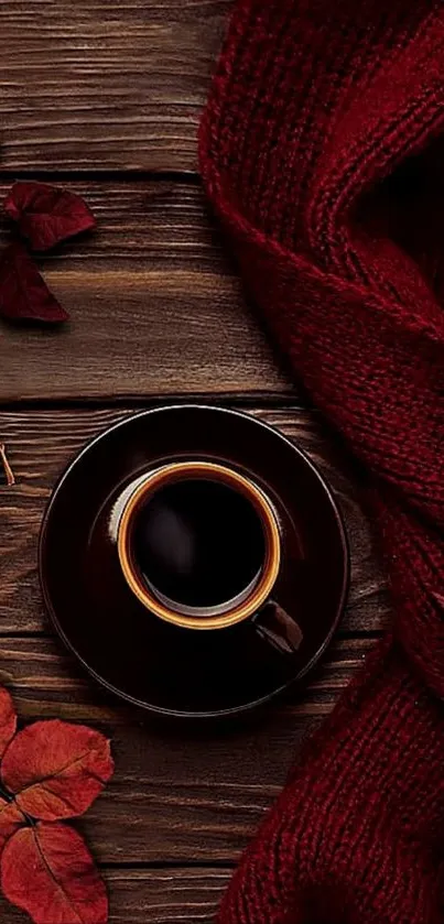 A cozy scene with coffee, red leaves, and a scarf on wooden background.