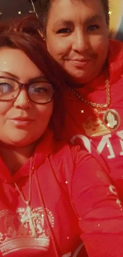 Two people in matching red hoodies with golden design accents.