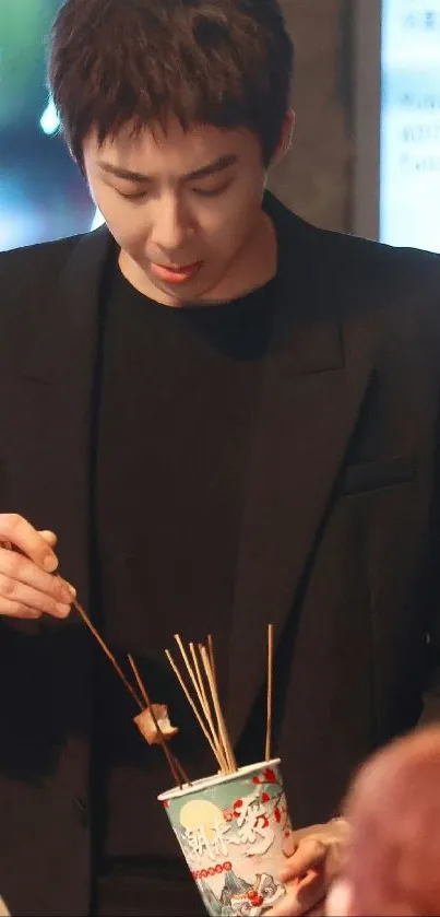 Person dining with skewers under dim lights.