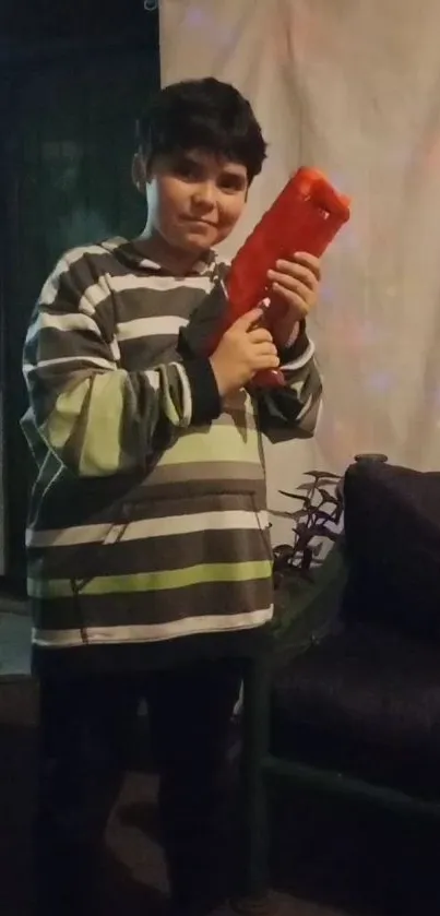 Child in striped sweater holding a toy indoors.