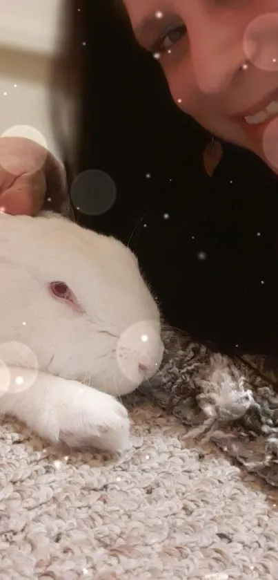 Person cuddling with a fluffy white bunny on a soft textured surface.