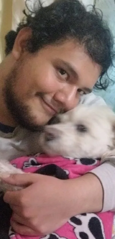 Man hugging his fluffy dog wrapped in a pink blanket.