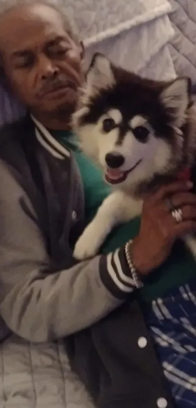 Man napping with husky puppy on gray blanket.