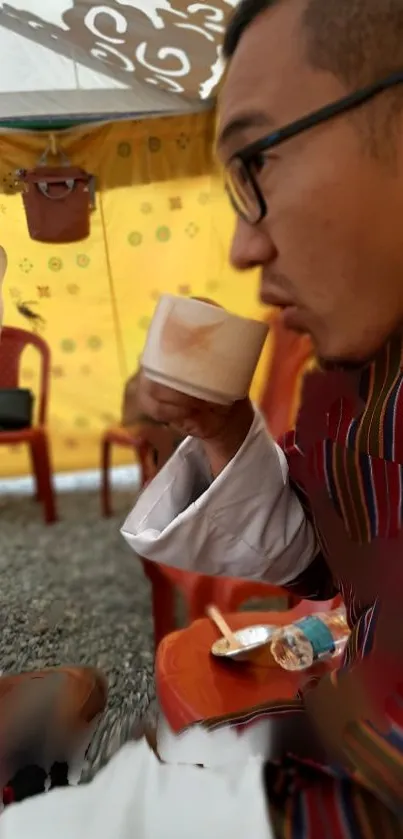 Man enjoying tea outdoors in colorful setup.