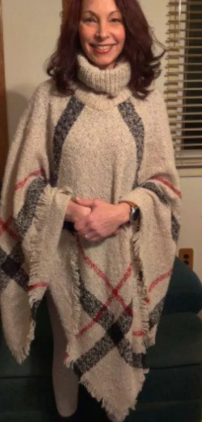 Woman wears a cozy plaid poncho in a home setting.