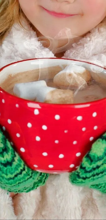 Child holding a red polka dot mug with green mittens.