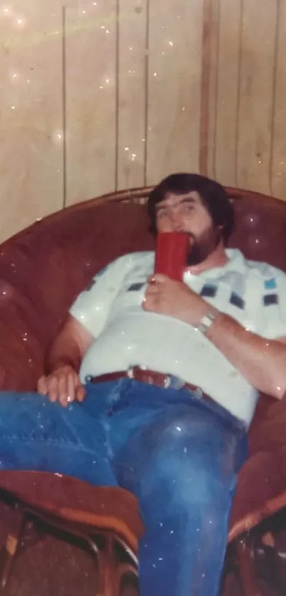 A man relaxing in a cozy vintage chair with a wooden wall background.