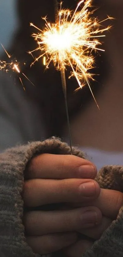 Hands holding a sparkler in cozy winter setting.