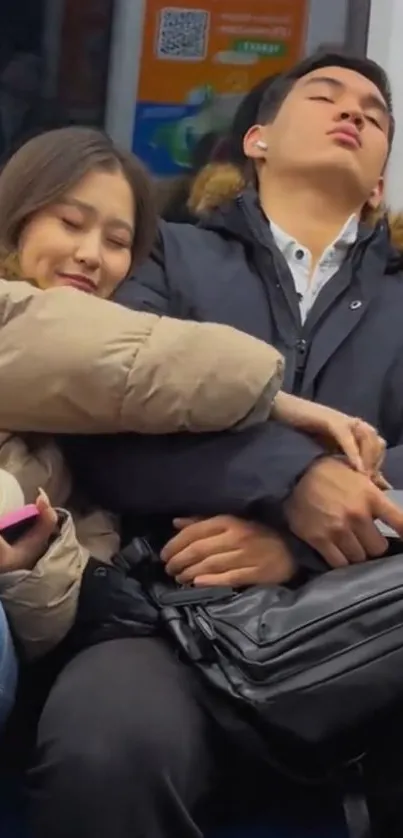 Two people resting on a subway wearing winter coats.