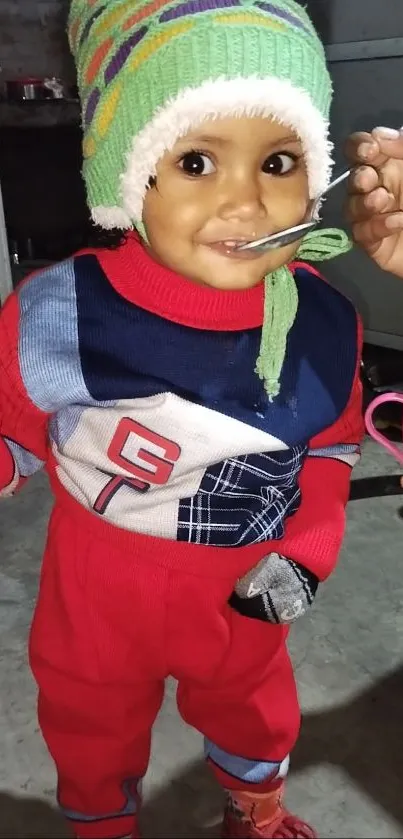 Adorable toddler in a red winter outfit with a knitted cap.