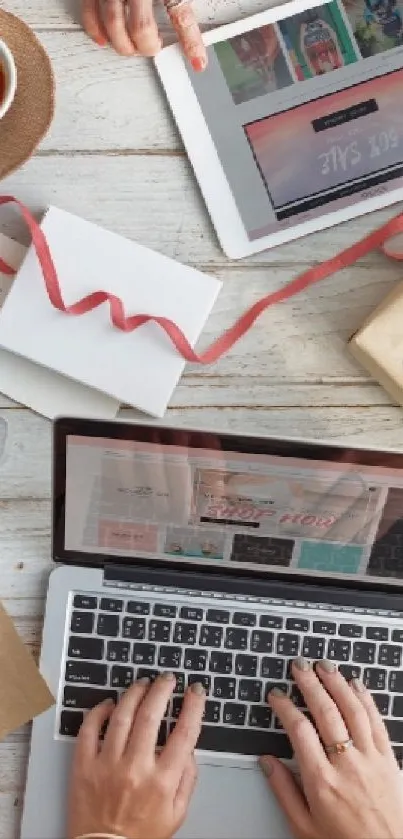 Cozy workspace with laptop, tablet, coffee, and gifts on a wooden table.