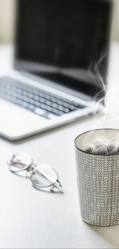 Cozy desk with coffee, laptop, and glasses.