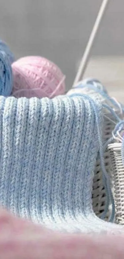 Soft pastel knitting theme with yarn balls in light blue and pink hues.