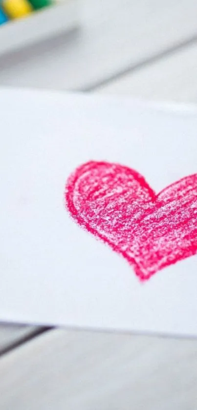 Pink crayon heart drawing on white paper background.