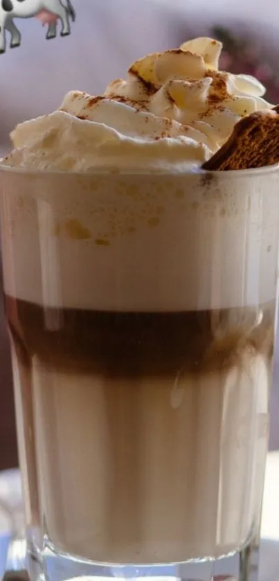 A glass latte topped with cream and a biscuit.