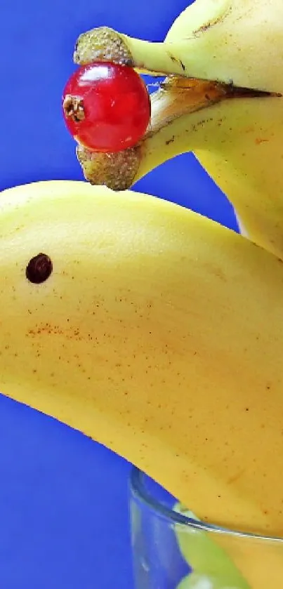 Bananas shaped as dolphins with grapes against a blue background.