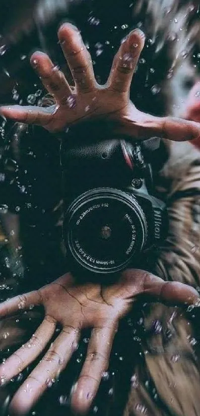 Creative hand holding a camera with water droplets in the background.