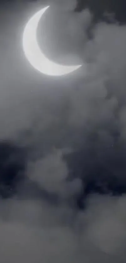 Crescent moon shining through dark clouds at night.