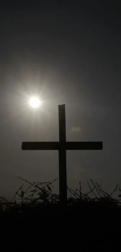 Silhouette of a cross against a bright sun.