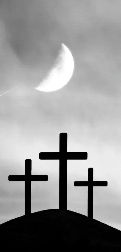 Silhouette of three crosses beneath a crescent moon.