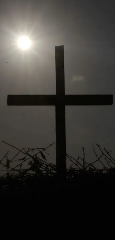 Silhouette of cross under bright sun on mobile wallpaper.