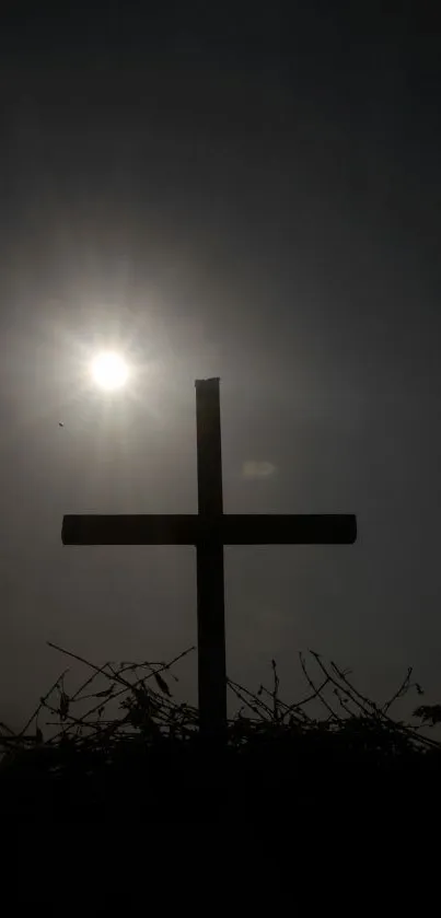 Silhouette of a cross with sun shining in the background.