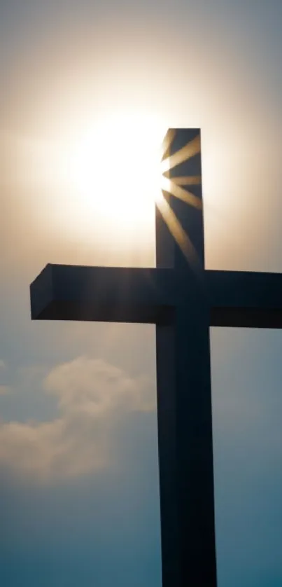 Silhouette of a cross with sun rays behind it against a blue sky.