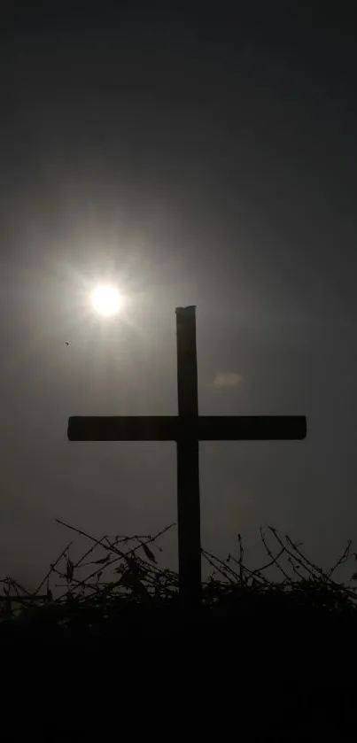 Silhouette of a cross with bright sun in the background.