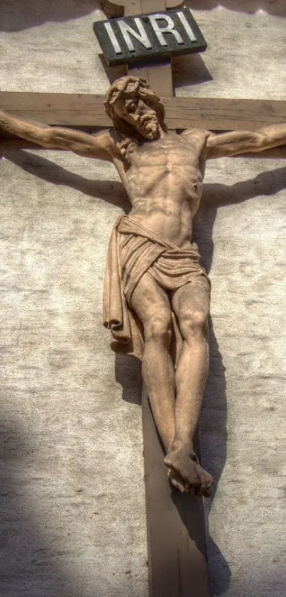 Religious sculpture of Jesus on a crucifix against a textured wall background.