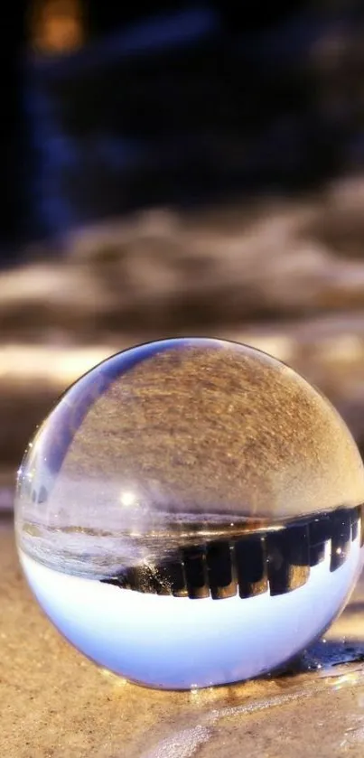 Crystal ball reflecting beach scene on sand.