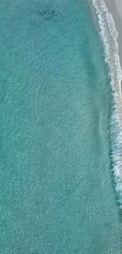 Aerial view of serene blue ocean waves on sandy beach.