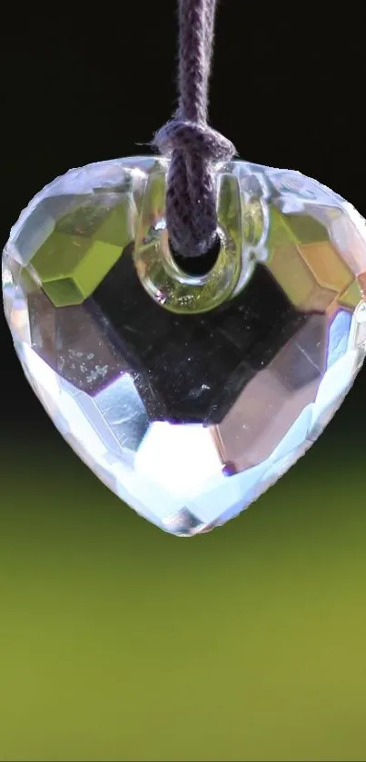 Crystal heart pendant against blurred green background.