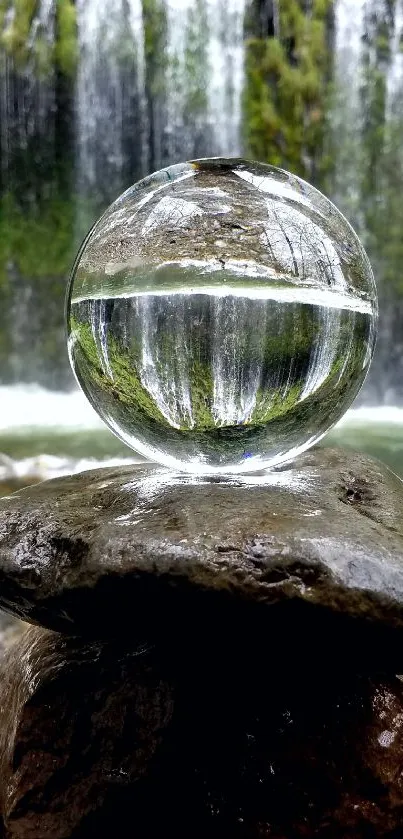 Crystal sphere reflecting waterfall scene on rocks.