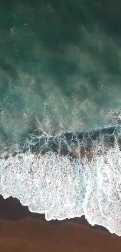 Aerial view of ocean waves crashing on sandy beach.