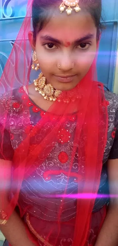 Girl in traditional red attire with intricate jewelry posing near a blue door.