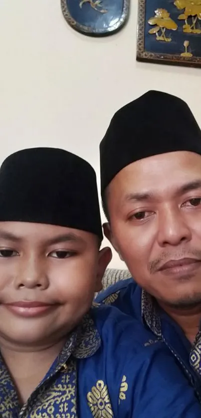 Father and son wearing traditional attire with decorative wall panels.