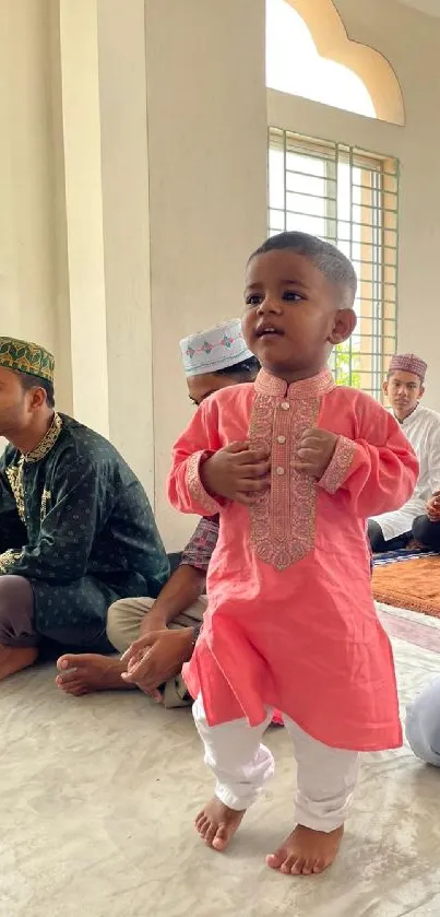 A child in pink traditional attire at a cultural gathering.