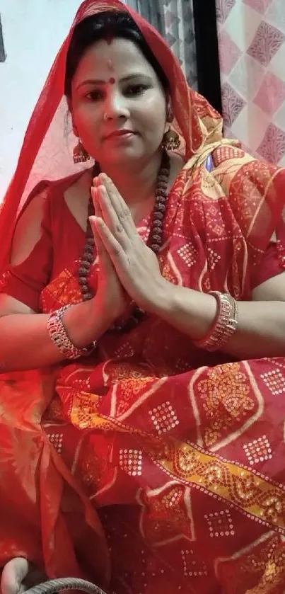 Woman in traditional red saree with intricate patterns and jewelry.