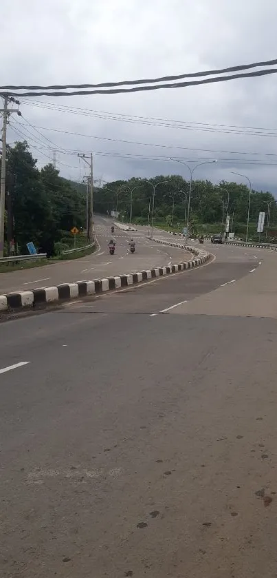 Curved road with cloudy sky and lush greenery background.