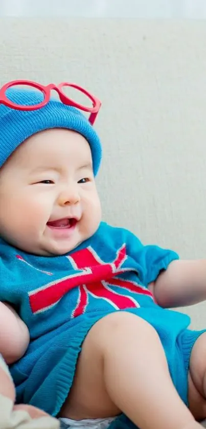 Cute baby wearing blue with red accents sitting happily.