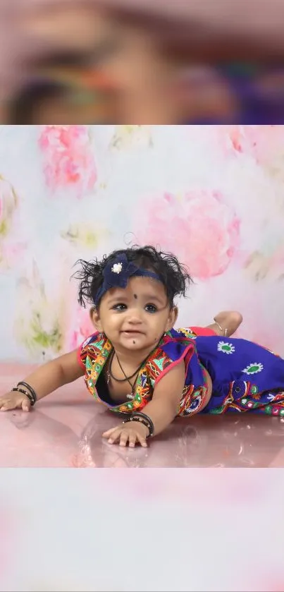 Adorable baby in floral outfit on pastel pink background.