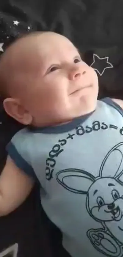 Smiling baby in cartoon bunny outfit on bed