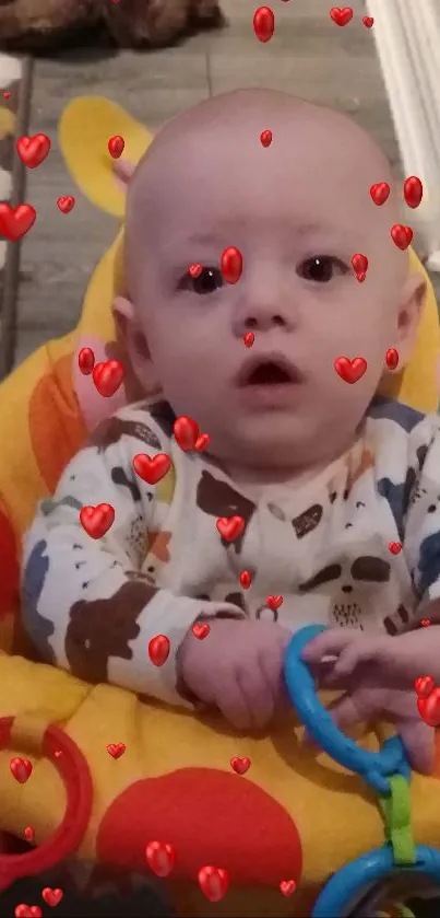 Baby surrounded by red hearts in a bright, colorful seat.