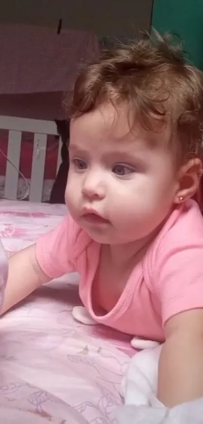 Adorable baby in a pink-themed room looking curious.