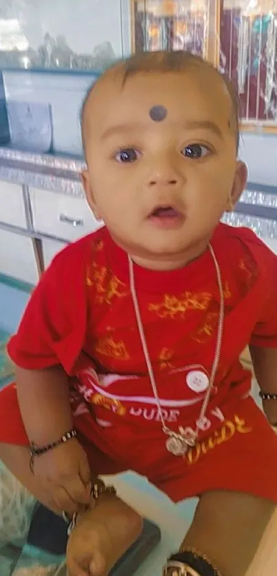 Cute baby in red outfit with jewelry inside a store.