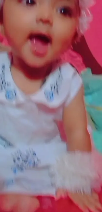 Smiling baby in white dress with pink background.