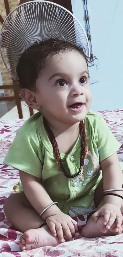 Adorable baby in green outfit smiling on floral bed.