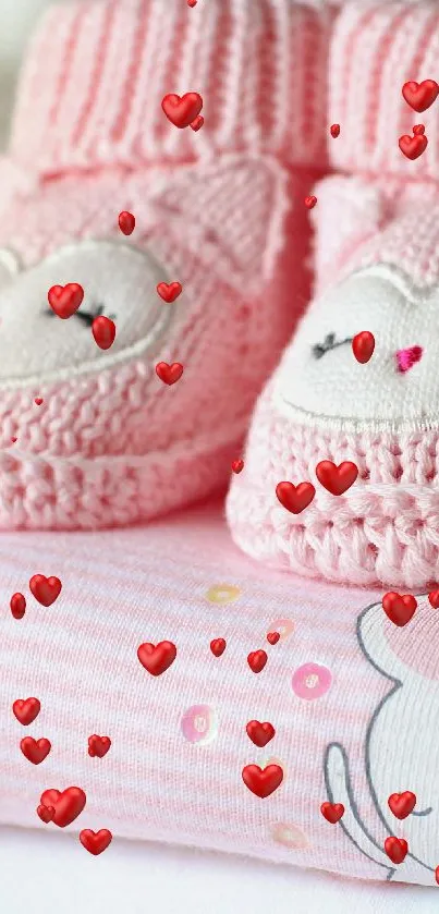 Pink knitted baby booties on stacked clothes.